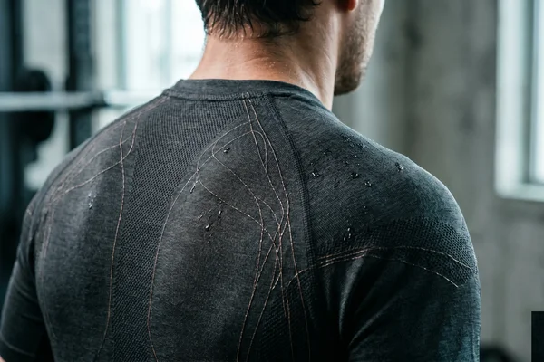 Functional training shirt with woven sweat-biomarker sensors and sweat droplets on the fabric
